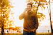 © anatoliycherkas - Portrait of handsome and happy guy smiling and talking on the phone in the autumn park
