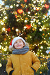 © Maria Sbytova - Little boy wearing a red Santa hat having fun with his family on traditional Christmas fair. Winter holiday traditions.