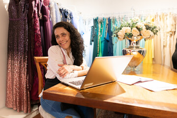 Happy latin female professional with big smile thinking about the future and planning inside business store. owner, small business, successful, community concept..