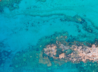 Wall Mural - An aerial view of the beautiful Mediterranean Sea, where you can see the cracked rocky textured underwater corals and the clean turquoise water of Protaras, Cyprus,