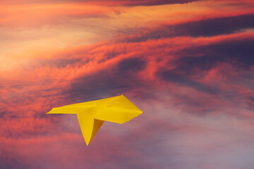 a small yellow paper plane flying over the red clouds on sunset time with high altitude, 3d illustration concept, business dream big concept