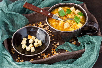 Wall Mural - Tasty yellow split pea soup with smoked bacon and toasts on wooden board in rustic style