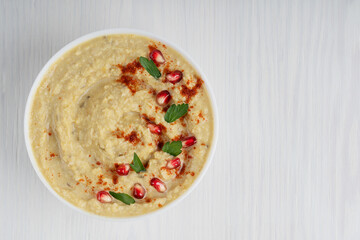 Canvas Print - Top view of single savory organic homemade hummus thick spread made from mashed chickpeas used especially as a dip decorated with pomegranate seeds and parsley served in bowl. Image with copy space