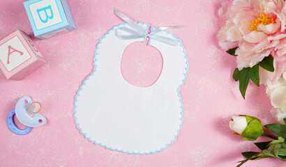 Wall Mural - Baby bib nursery clothing mom bloggers desktop mockups with peonie floers on pink textured background. Top view blog hero header creative composition flat lay. Negative copy space mock up.