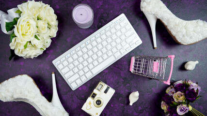Wall Mural - Wedding bridal theme desktop workspace with high heel shoes, bouquets and accessories, and shopping cart on vintage purple textured background. Top view blog hero header creative composition flat lay.
