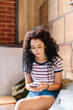© Kristen Curette Photography LLC/Stocksy - A young hispanic woman looking down at her phone in a cafe