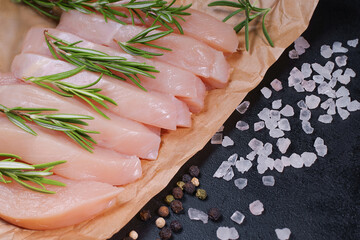 Raw organic chicken breast on a dark background.Top view .Raw chicken steaks on a black background with spices and salt. Chicken pieces.