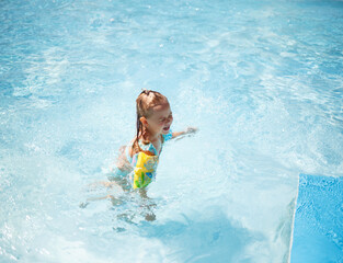 little girl swims in the pool in the outdoor water park