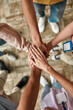 © Svitlana - Top view of diverse young volunteers putting their hands on top of each other like a real team while standing in charitable organization office