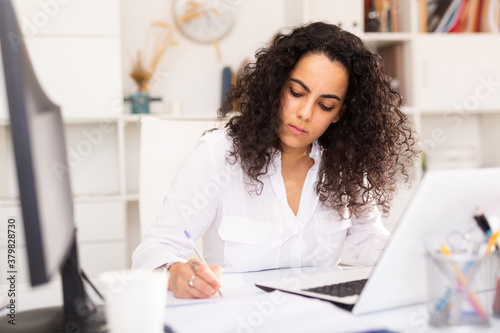 Fotografía Portrait of young female business employee writing and working with laptop at of