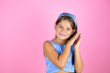 Young beautiful child girl over isolated pink background clapping and applauding happy and joyful, smiling proud hands together