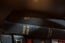 Ray Of Sunlight On A Bible Which Is Lying Across Other Book In A Bookcase