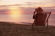 © New Africa - Woman relaxing on deck chair at sandy beach. Summer vacation
