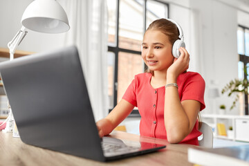 Wall Mural - children, education and distant learning concept - happy smiling teenage student girl in headphones with laptop computer at home