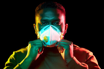 health, safety and pandemic concept - young african american man wearing protective mask or respirator over black background