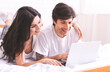 © Prostock-studio - Young couple browsing on laptop in bed