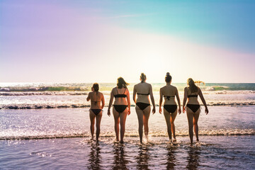 Five young women enter the sea at the beach on a beautiful summer afternoon