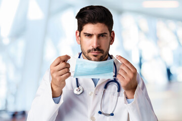 Portrait of male doctor while putting on face mask