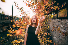 Ginger Woman Posing With A Yellow Bush Behind At Sunset