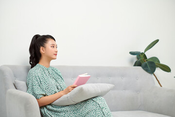 Wall Mural - Beautiful girl on a white sofa reading a book