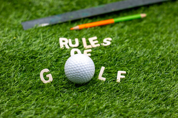 Rules of Golf with golf ball and tee on green grass