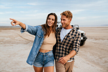 Young happy loving couple outdoors at beach near car walking