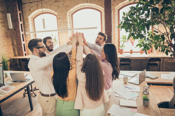 Photo of business men ladies people corporate atmosphere spacious office diversity members best friends clap arms overjoyed successful project startup teammates professionals indoors