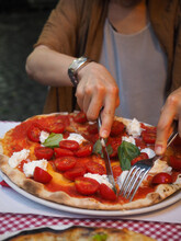Woman's Hands Cutting Fresh Pizza