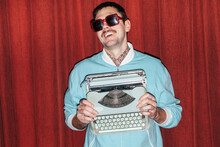 Funny Smiling Handsome Man Posing In Blue Jacket Holding Vintage Typewriter In Hands
