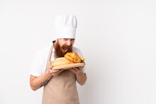 Redhead Man In Chef Uniform. Male Baker Holding A Table With Several Breads