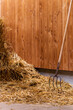 Pitchfork in straw. Pitch Fork stuck into a pile of sunlit straw down on a farm. Concepts of harvesting season, agricultural stable work with farm tools, preparation of animal feed. Copy space.