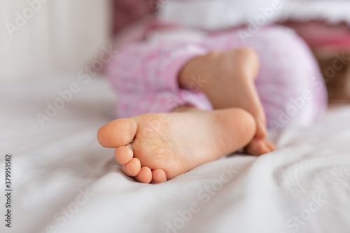 Fotomural Feet of a girl sleeping in a comfortable bed. Focus on the foot