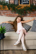 A little girl is sitting on a cozy sofa with checkered pillows