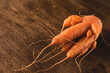 Ugly carrot on a wooden background. Funny, unnormal vegetable or food waste concept. Horizontal orientation