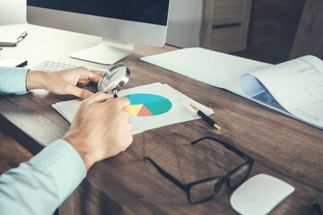 Poster - man using magnifier and financial graph.