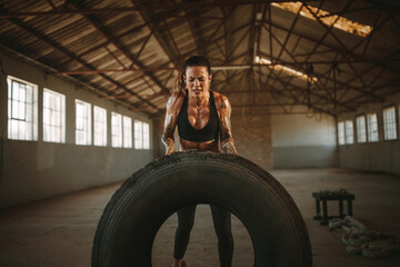 Wall Mural - Muscular female working out with big tire