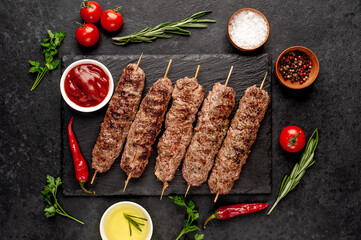 Wall Mural - grilled Lula kebab on skewers with spices on a stone background

