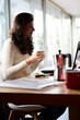 © Guille Faingold/Stocksy - smiling girl with cup in hands sitting at workplace