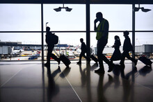 Silhouettes Of Air Travelers Navigating The Terminal To Board Airplane Flights Amid Pandemic.