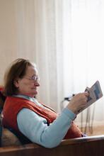 Senior Woman Sitting In Her Living Room Reading Newspapers