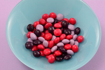 Wall Mural - Strawberry, blackberry and raspberry fruit candies in blue bowl on lavender background