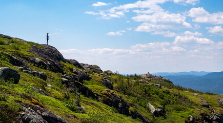 Wall Mural - Panoramic view of a silhouette of a woman standing at the top of a mountain in the Hautes-gorges-de-la-rivière-Malbaie national park, Quebec