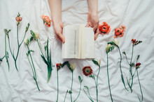 Book On A Bed Surrounded By Orange And Green Flowers
