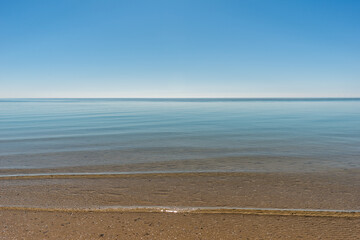 Sand beach background in Denmark. Sunny day on the sea coast. Blue Sky without clouds. Calm water background