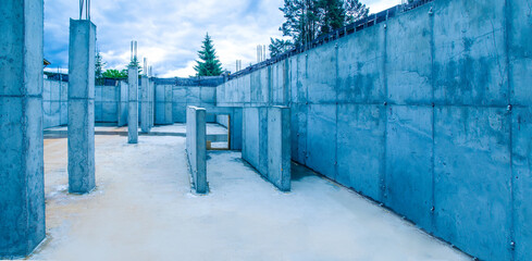 Poster - Erection buildings. Construction site. There is no one inside building under construction. Erection home made of concrete. Fir trees and sky in background. Concept - construction services.