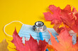 © Natasha - disposable protective medical mask and stethoscope and autumn maple leaves on yellow background copy location, seasonal colds concept, coronavirus 2020 pandemic