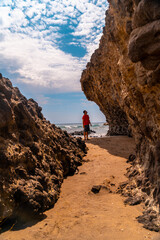 Wall Mural - A young man enjoying the beautiful rocks on the shoreline at Cala de la Media Luna in Cabo de Gata Natural Park, Nijar, Andalucia. Spain, Mediterranean Sea