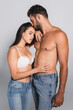 © LIGHTFIELD STUDIOS - seductive woman in bra touching muscular man with closed eyes standing on grey