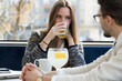© Guille Faingold/Stocksy - Young business couple drinking something at a coffee shop.