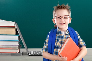 Wall Mural - Stack of books with laptop on table and cute school boy